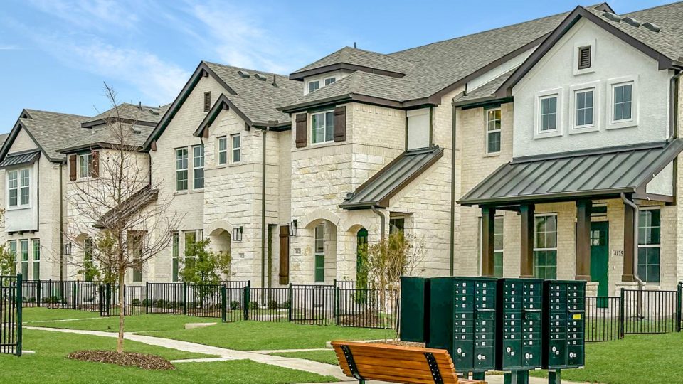 a park bench sits in front of a row of townhomes at The Villas at Bardin