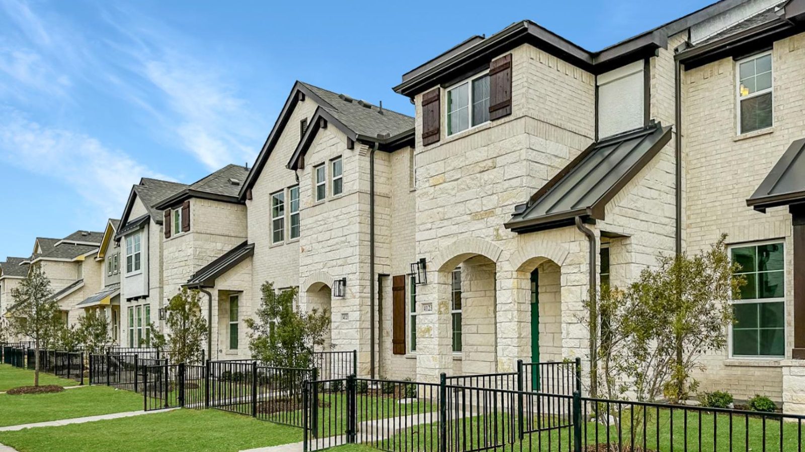 a row of townhouses with a fence and grass at The Villas at Bardin