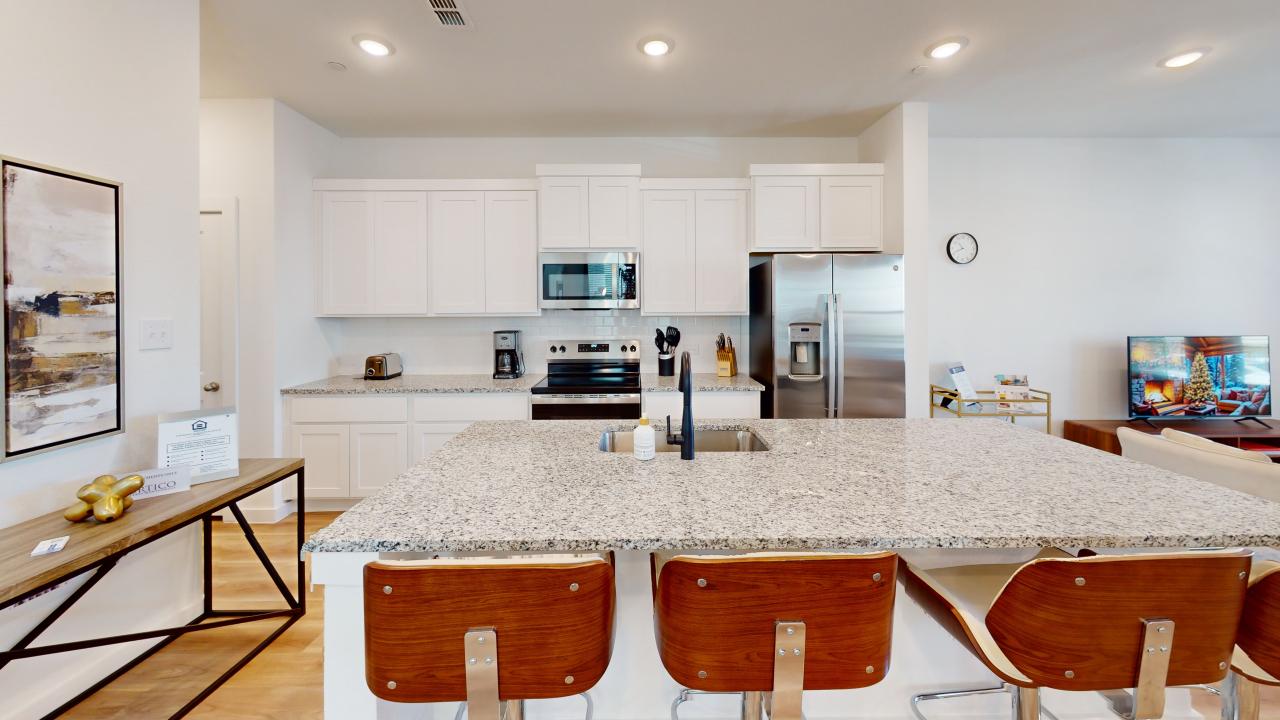 a kitchen with white cabinets and a bar stool at The Villas at Bardin