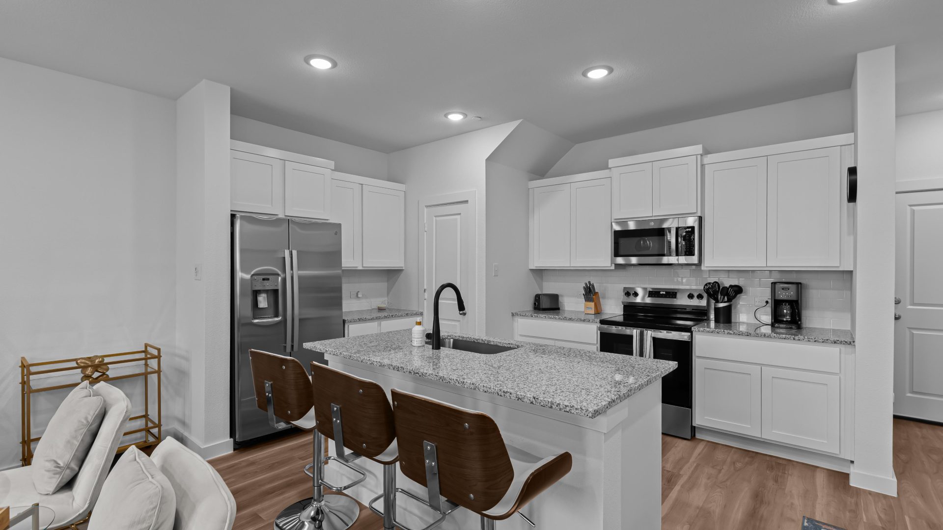 a white kitchen with a center island and bar stools at The Villas at Bardin